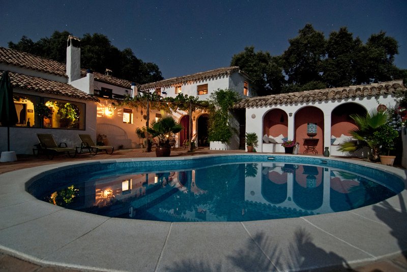 Spanish style white mansion at night with pool